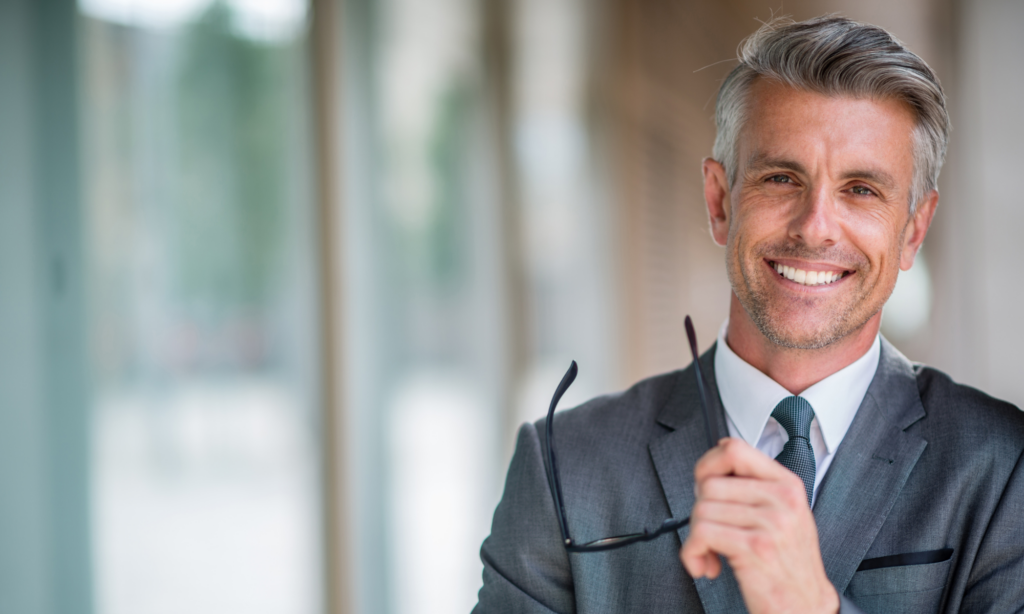 Untitled-design-2024-09-28T165829.196-1024x614 a man smiling while holding his sun glasses